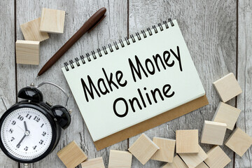 Make money online text with spring on wooden background near alarm clock and wooden blocks