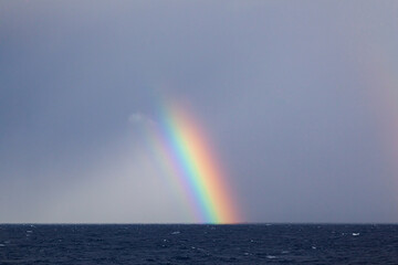 Part of a bright colorful rainbow in the open sea.