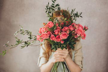 Girl with a bouquet of flowers covers her face