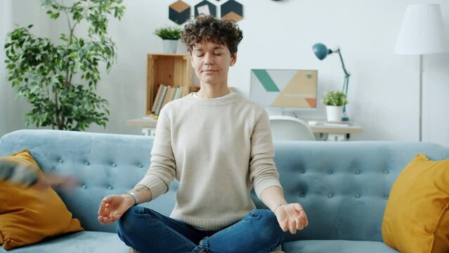 Young woman meditating in lotus position relaxing managing stress while hyperactive child running screaming at home. Family lifestyle and covid-19 quarantine concept.