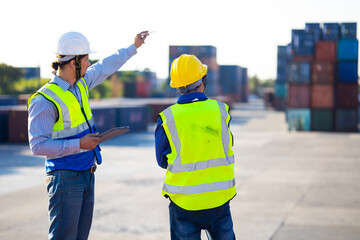 Two caucasian man engineer worker wearing hardhat safety helmet and vest working in  logistic shipping yard. Marine and carrier insurance concept. Cargo container yard.