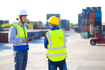 Two caucasian man engineer worker wearing hardhat safety helmet and vest working in  logistic shipping yard. Marine and carrier insurance concept. Cargo container yard.