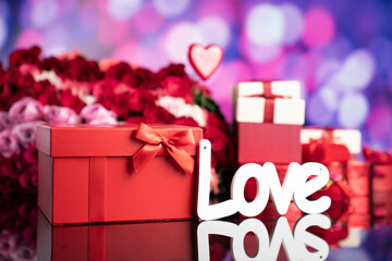 Valentines day concept. Gifts in boxes, red hearts and big bouquet of natural roses on blue bokeh background.