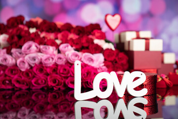 Valentines day concept. Gifts in boxes, red hearts and big bouquet of natural roses on blue bokeh background.