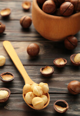 Macadamia in wooden spoon on brown background. Favorite for snack and very delicious.Have a lot of unsaturated fatty acid. Healthy food concept. Vertical photo