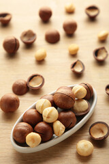 Peeled macadamia nuts on plate on light background. Vertical photo