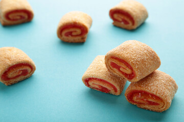 Homemade cookies, mini rolls with apricot jam on blue background. Top view