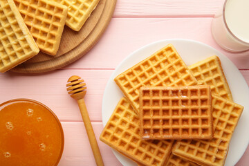 Belgian waffles on pink background. Belgian waffles with honey and milk. Freshly baked Belgian waffles.