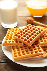 Belgian waffles on brown background. Belgian waffles with honey and milk. Freshly baked Belgian waffles. Vertical photo