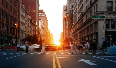 Sunlight shining on the people and cars at a busy intersection on 5th Avenue in Manhattan, New York City
