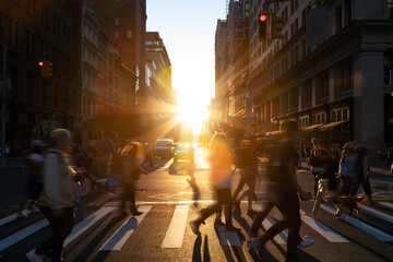 Diverse group of people walking across the crowded intersection at 23rd Street and 5th Avenue in New York City with light of sunshine in the background