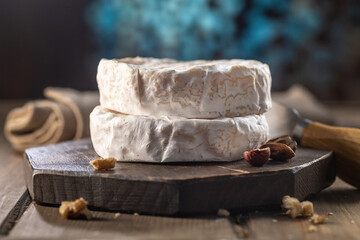 Organic homemade camembert or brie cheese on a wooden board with grapes and nuts and honey.