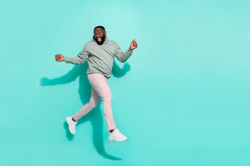 Fototapeta na wymiar Full length body size view of attractive cheerful guy jumping going enjoying isolated over bright teal turquoise color background