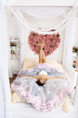 Beautiful cute girl in a luxurious dress lying on a decorated bed