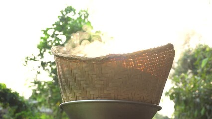 Steamed sticky rice. Steam generated by heat. Old sticky rice steaming pot. Black pot boiling water for cooking on the fired stove on black background. Thailand Esan traditional culture ancient method