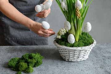 Easter floral DIY composition for table centerpiece with white eggs, moss and bunny. Close up. Woman make spring decor.