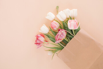 Minimal neutral beige background. Top view of bunch of flowers in paper bag mock up. Flat lay, copy space.
