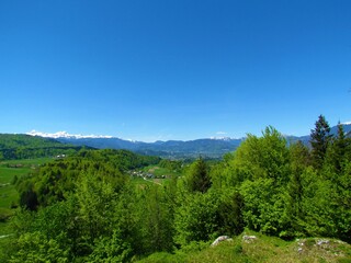 Fototapeta na wymiar Beautiful panoramic view of Gorenjska, Slovenia with forests and snow covered mountain peak of Triglav mountain