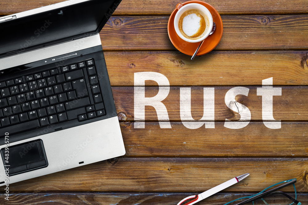 Wall mural rust programming language. word rust on wooden desk and laptop
