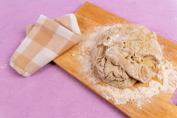 Raw dough purple concrete background, cooking bread, pizza. Copy space.