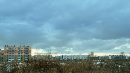 Fototapeta na wymiar Winter countryside landscape and residential buildings under a gloomy cloudy sky