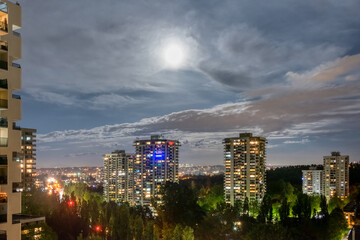Night cityscape with full moon in clouds