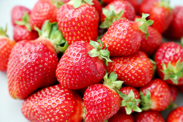 Fresh red strawberries with leaves. Pile of ripe strawberry for background