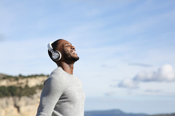 Happy man breathing listening to music outdoors