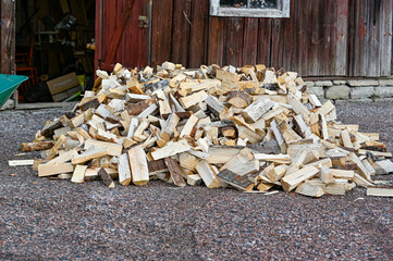 big pile of firewood infront of red barn