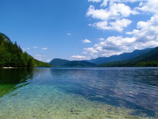 View of famous tourist destination Bohinj lake in Gorenjska, Slovenia with a reflection of the clouds in the lake