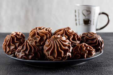 Chocolate marshmallows in a plate on a light background. Side view. Sweet food concept.