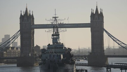 A navy ship in front of the Tower Bridge at sunset. - Powered by Adobe