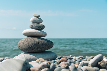 Fototapeta premium Pebble tower stands on the seashore on a sunny day, copy space. Concept of banas and harmony.