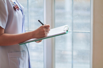 The doctor holds a clipboard containing the patient's test results in the office to diagnose the condition and the doctor will perform the correct treatment for the patient's safety.
