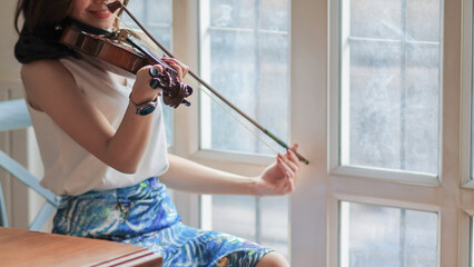 young female violinist is practicing violin in music practice room in preparation for concert and...