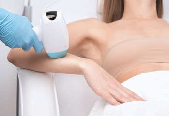 Naklejka premium Elos epilation hair removal procedure on a woman’s body. Beautician doing laser rejuvenation on the lower leg in a beauty salon. Removing unwanted body hair. Hardware ipl cosmetology
