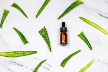 Bottle with products for spa or skin care cosmetic. Aloe vera gel or oil and Aloe Vera leaves on white marble background.flat lay,top view image.