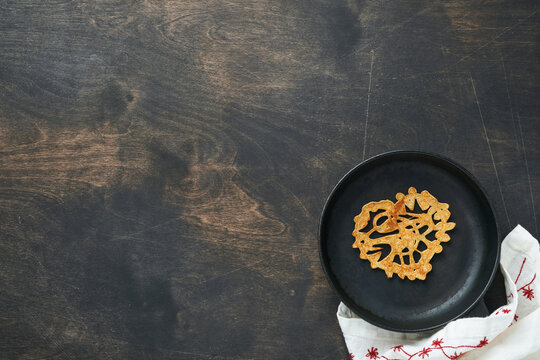 Heart shaped lace pancakes or crepes on cast iron skillet on old wooden rustic background. Table setting for your favorite Valentines Day breakfast. Top view copy space.