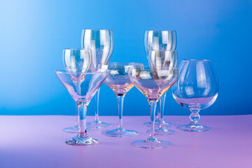Empty various cocktail glasses on blue and pink background