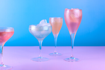 Various cocktail glasses with colorful drink on blue and pink background. Cocktail party concept