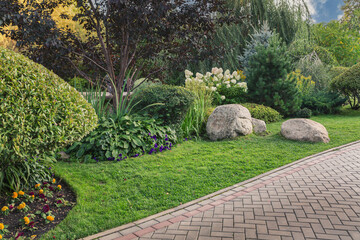 Fototapeta premium Paved alley of the park with trimmed bushes and trees. Topiary art. Landscaping.