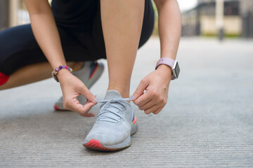 Young female tying running shoes before running.