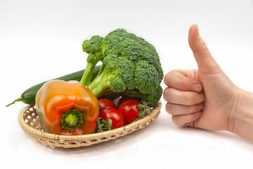 Fresh broccoli, cucumber, pepper and tomatoes on a wicker basket on white background
