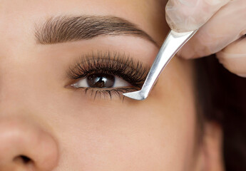 Extension of the lower eyelashes. a young woman undergoes a close-up eyelash extension procedure. Tweezers. Down below