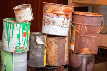A collection of paint cans, buckets, toxic and hazardous material stacked. Hazardous waste.