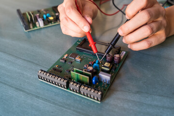 Woman hands measuring an intercom motherboard electric current
