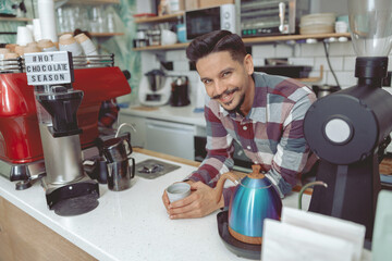 Happy barista holding cup of coffee in cafe