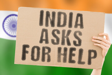 The phrase " India asks for help " on a banner in men's hand with blurred Indian flag on the background. Battle. Combat. Tension. Voice. Aggression. Violence. Relationship. Society. Relation