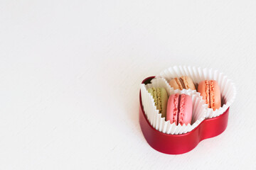 Colorful fresh french macaroons in a heart shape box on white wooden background, gift idea, Valentine's Day, March 8