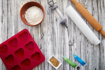 Preparing for baking: heart-shaped silicone mold, rolling pin, confectionery syringe, glaze, flour, sugar. Valentine's day concept. High quality photo